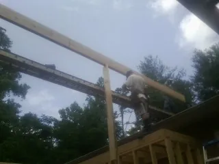 Carpenter setting a ridge beam over a new addition frame — Ice Dam Removal by Roofing Brothers in Valhermoso Springs