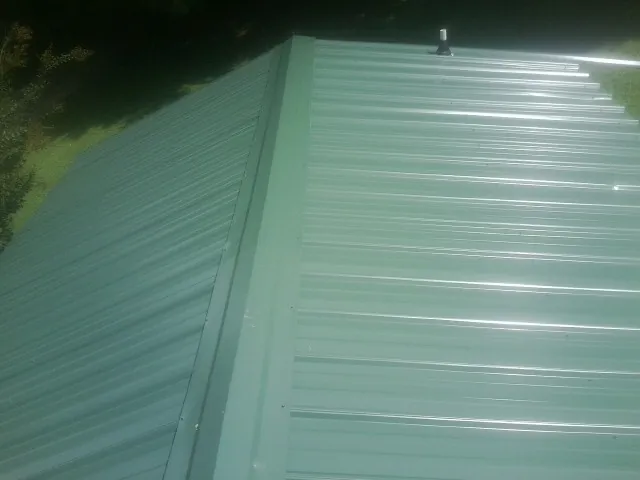New green metal panels meeting at the ridge of a roof — Flat Roof Repair work by our crew in Valhermoso Springs