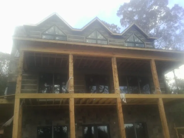 Dormers and porch framing on a large log home under construction — Roof Coating work by our crew in Valhermoso Springs