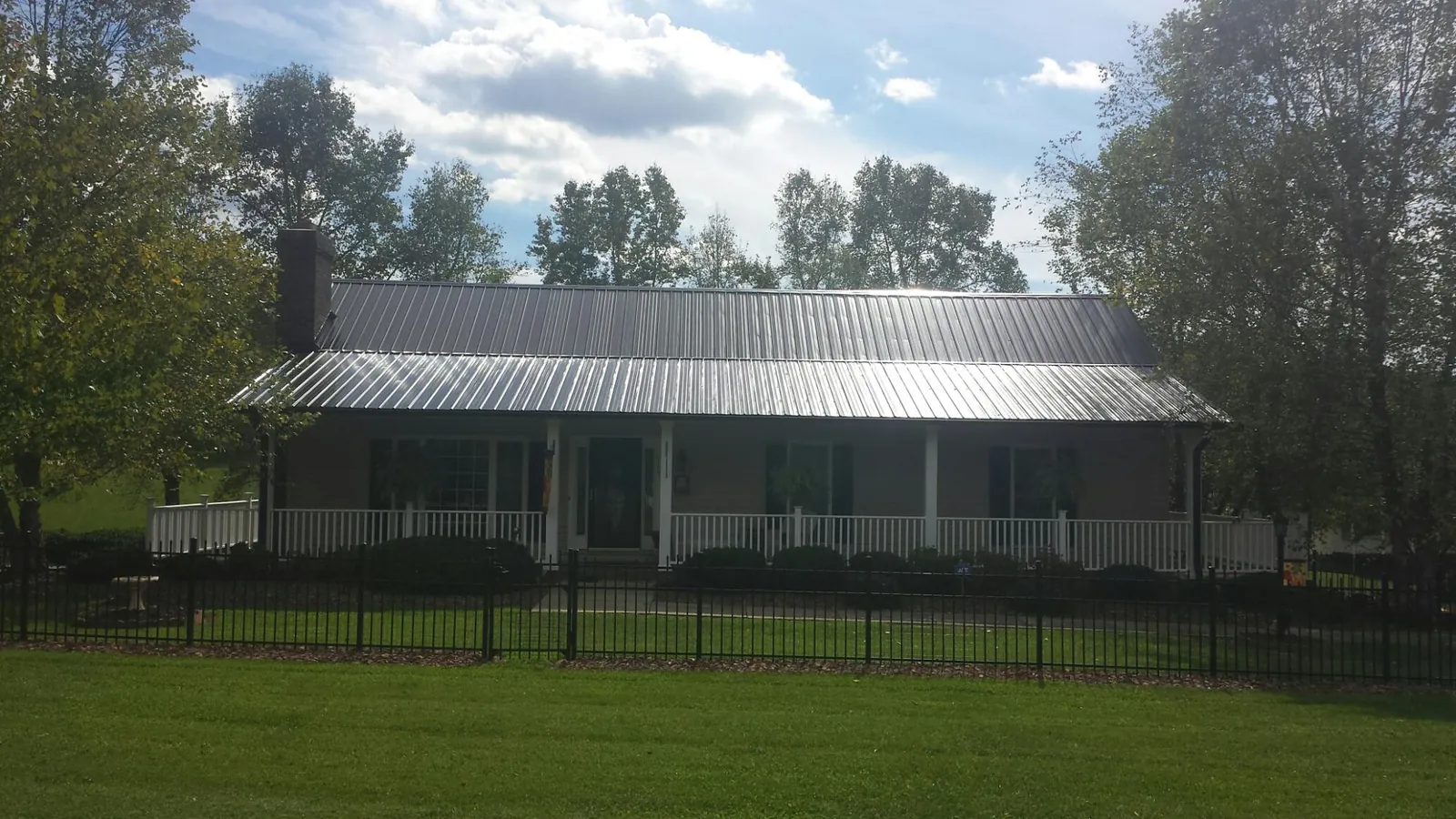 Gray metal roof on a brick ranch with a full width front porch — Gutter Guard Installation work by our crew in Valhermoso Springs