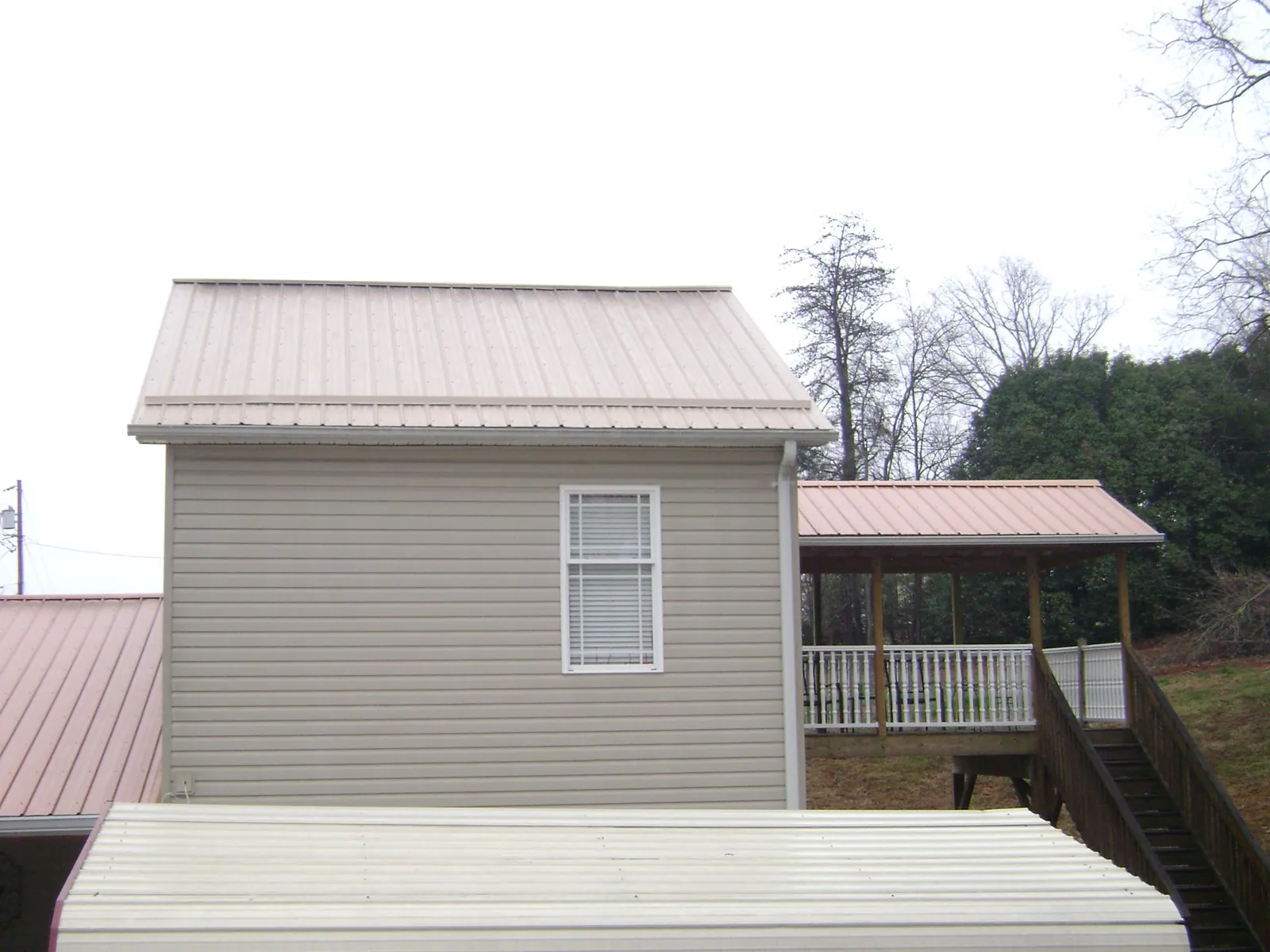 Tan metal roofs on a two story addition and attached porch, from a Roof Replacement job in Valhermoso Springs